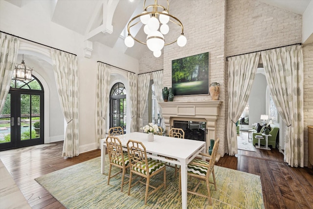 dining area featuring arched walkways, hardwood / wood-style floors, an inviting chandelier, french doors, and high vaulted ceiling