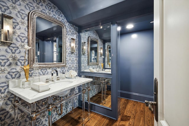 bathroom featuring baseboards, wood finished floors, vanity, and wallpapered walls