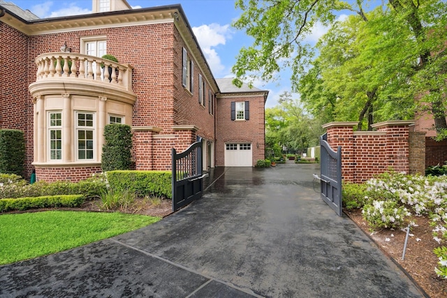 view of side of property featuring a garage, a gate, and brick siding