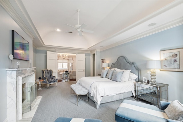 bedroom featuring ornamental molding, a tray ceiling, vaulted ceiling, a fireplace, and ceiling fan with notable chandelier