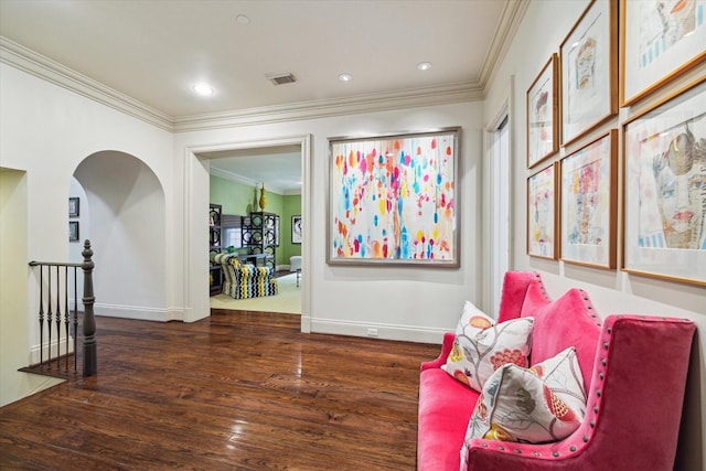 sitting room with baseboards, visible vents, wood finished floors, and ornamental molding