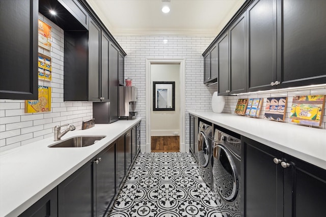 clothes washing area with brick wall, a sink, ornamental molding, cabinet space, and washing machine and clothes dryer