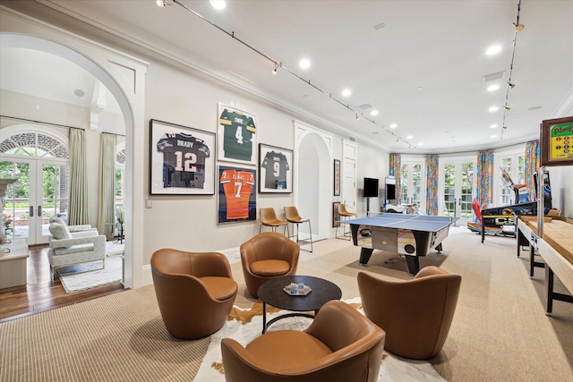 recreation room featuring arched walkways, french doors, rail lighting, light carpet, and baseboards