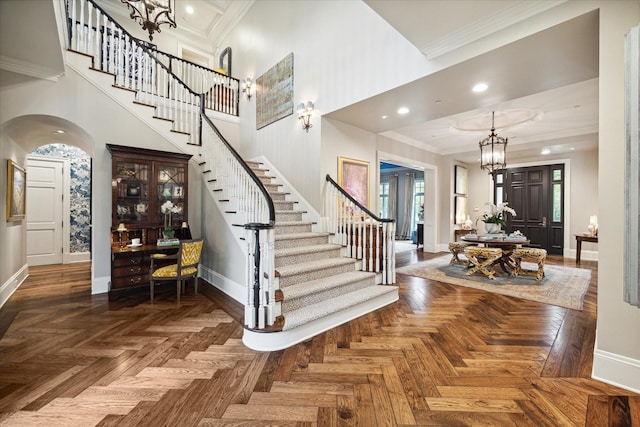 foyer with baseboards, an inviting chandelier, a high ceiling, stairs, and crown molding