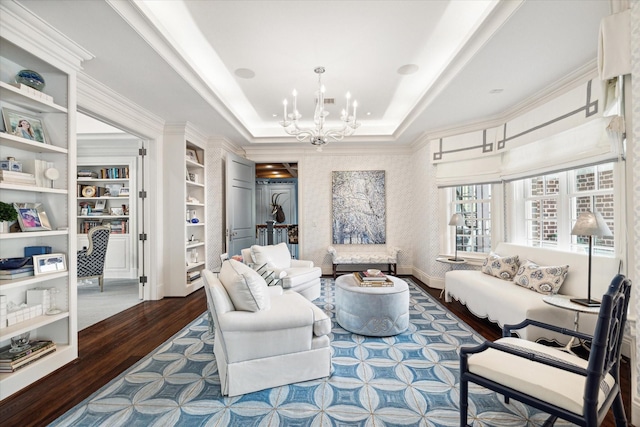 living room featuring a tray ceiling, wallpapered walls, an inviting chandelier, and wood finished floors