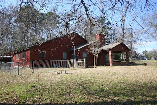 view of side of home featuring a chimney, fence, and a yard