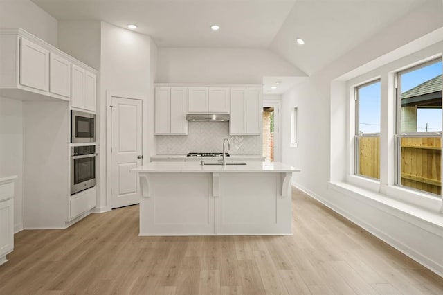 4918 Shore Arbor Ln, Katy, TX 77493 - kitchen with appliances with stainless steel finishes, light countertops, white cabinetry, tasteful backsplash, and light wood-style flooring