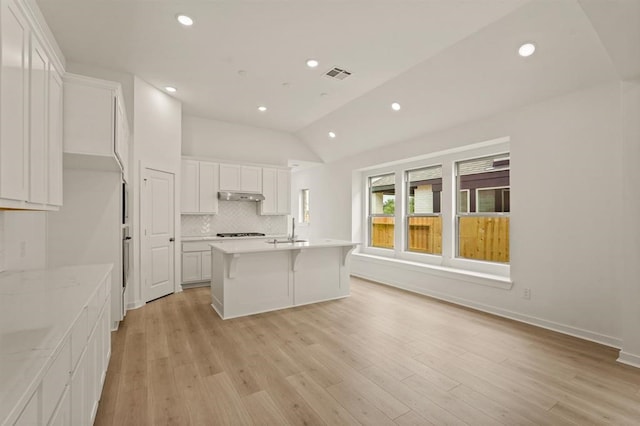 4918 Shore Arbor Ln, Katy, TX 77493 - kitchen with a sink, under cabinet range hood, vaulted ceiling, decorative backsplash, and white cabinets