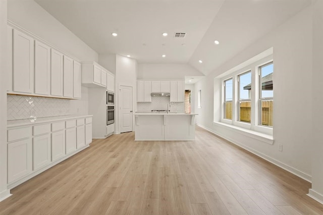 4918 Shore Arbor Ln, Katy, TX 77493 - kitchen with backsplash, light countertops, white cabinetry, lofted ceiling, and stainless steel appliances