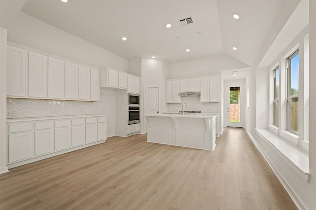 4918 Shore Arbor Ln, Katy, TX 77493 - kitchen featuring appliances with stainless steel finishes, decorative backsplash, white cabinets, lofted ceiling, and light wood finished floors