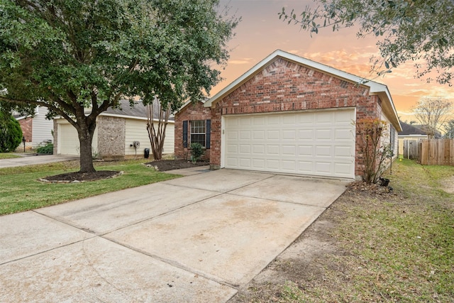 single story home with brick siding, an attached garage, a front yard, fence, and driveway