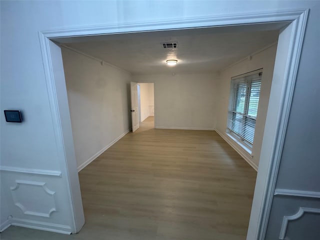 corridor with wood finished floors, visible vents, and baseboards