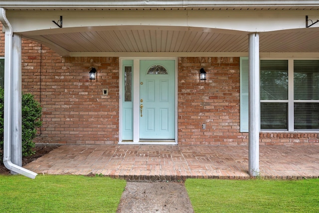 doorway to property with covered porch and brick siding