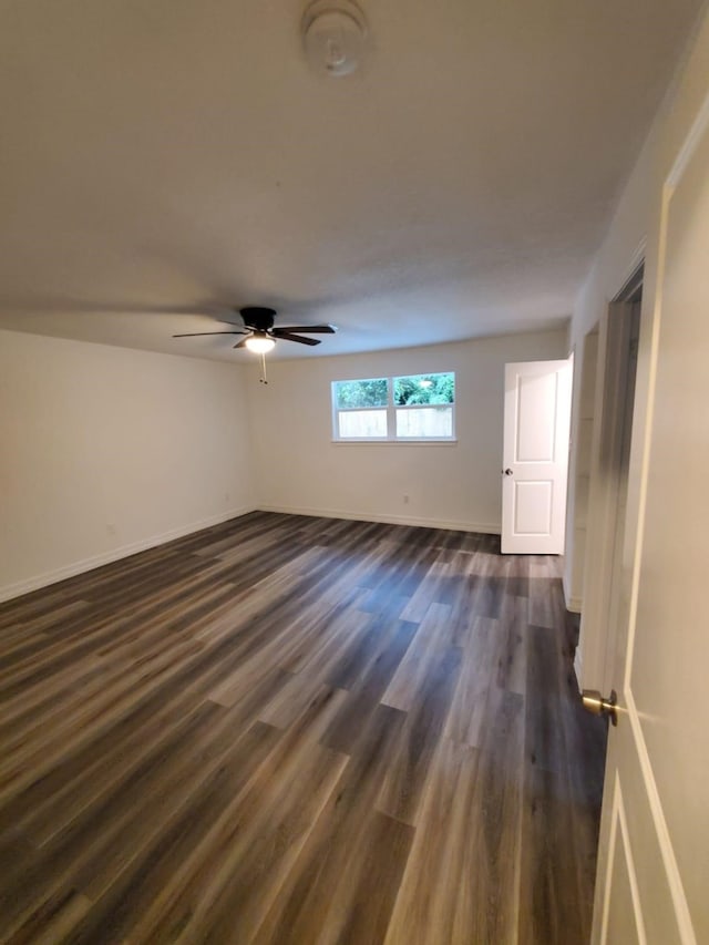 unfurnished room with a ceiling fan, dark wood finished floors, and baseboards