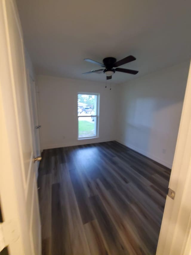 unfurnished room featuring dark wood-style floors, baseboards, and a ceiling fan