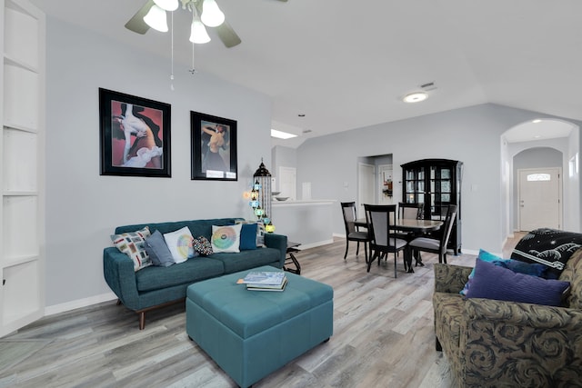 living room featuring lofted ceiling, light wood-style floors, ceiling fan, and arched walkways