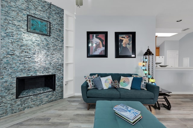 living room with built in features, wood finished floors, visible vents, baseboards, and a tile fireplace