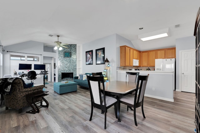 dining area featuring light wood finished floors, visible vents, a ceiling fan, and lofted ceiling