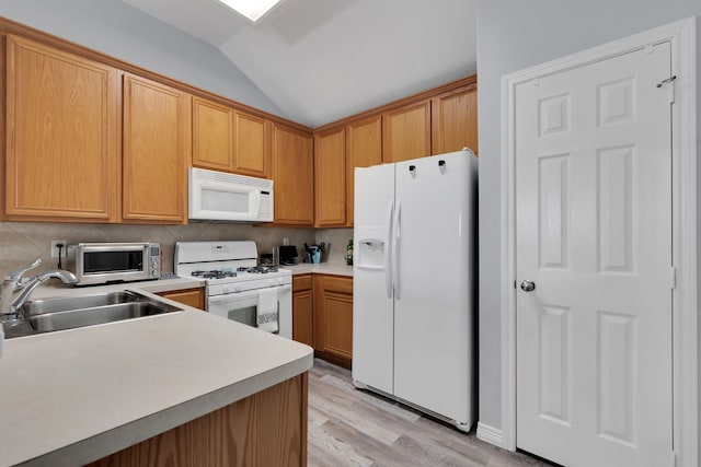 kitchen featuring tasteful backsplash, light countertops, lofted ceiling, white appliances, and a sink