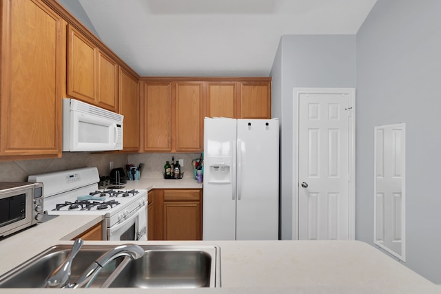 kitchen with a sink, white appliances, brown cabinetry, light countertops, and decorative backsplash