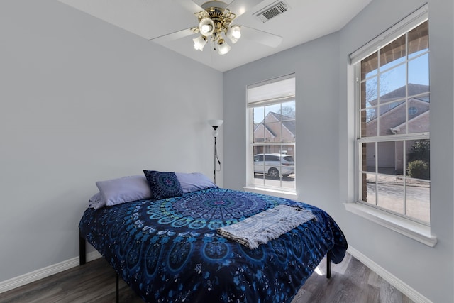 bedroom featuring visible vents, ceiling fan, baseboards, and wood finished floors