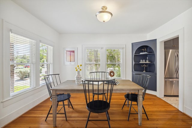 dining room featuring baseboards, built in shelves, and wood finished floors