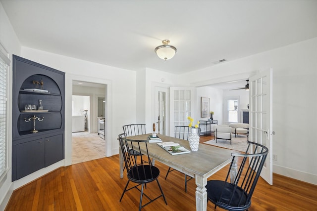 dining space featuring visible vents, baseboards, french doors, wood finished floors, and a ceiling fan