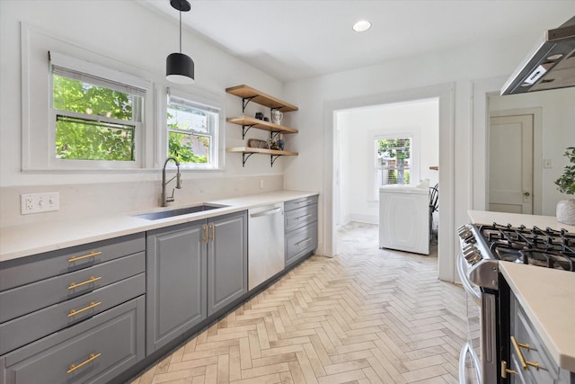 kitchen featuring washer / dryer, gray cabinets, a sink, under cabinet range hood, and appliances with stainless steel finishes