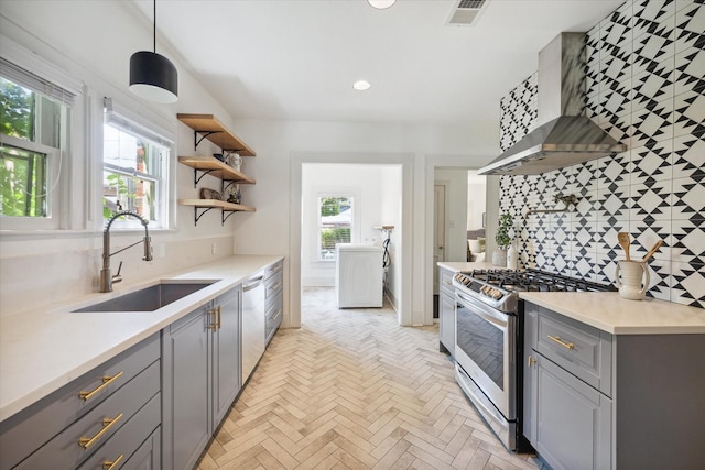 kitchen featuring visible vents, gray cabinetry, appliances with stainless steel finishes, wall chimney exhaust hood, and a sink