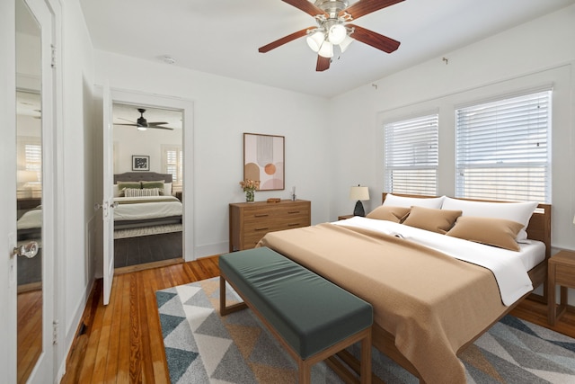 bedroom featuring baseboards, wood finished floors, and a ceiling fan