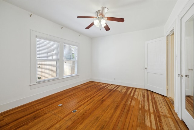 spare room featuring light wood-type flooring, baseboards, and a ceiling fan