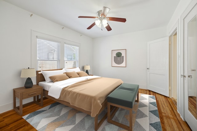 bedroom with baseboards, a ceiling fan, and wood-type flooring