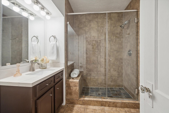 bathroom with a shower stall, a textured ceiling, and vanity