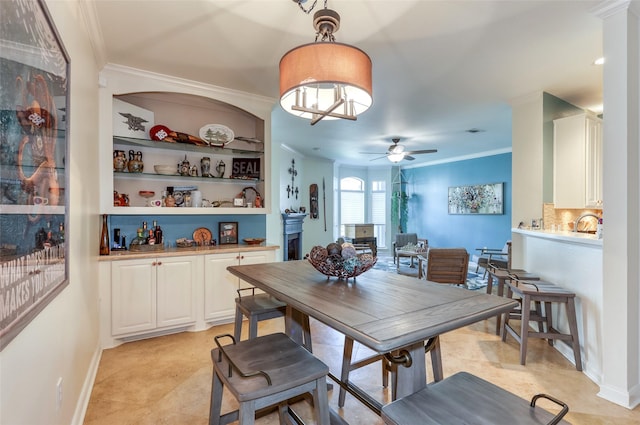 dining space featuring a ceiling fan, crown molding, and baseboards