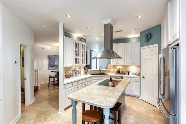 kitchen featuring black electric stovetop, a sink, visible vents, freestanding refrigerator, and tasteful backsplash