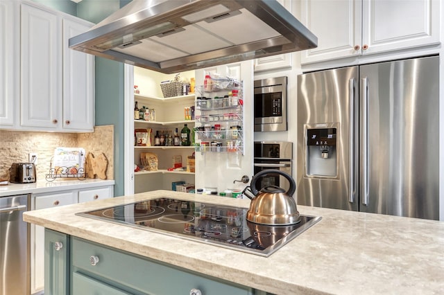 kitchen featuring stainless steel appliances, white cabinetry, light countertops, wall chimney range hood, and decorative backsplash