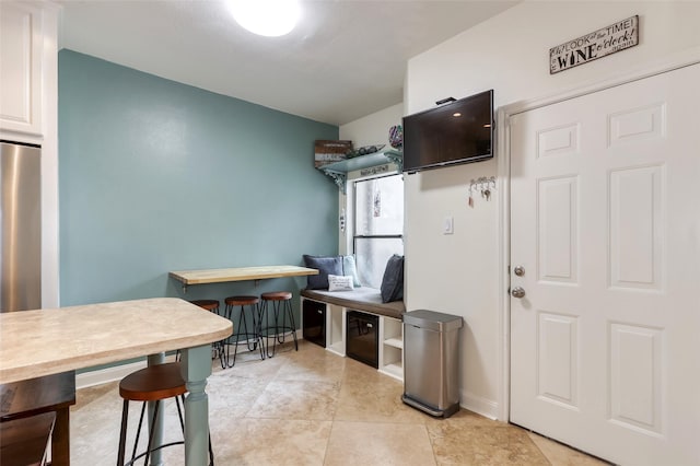 kitchen with light tile patterned flooring, baseboards, and stainless steel refrigerator