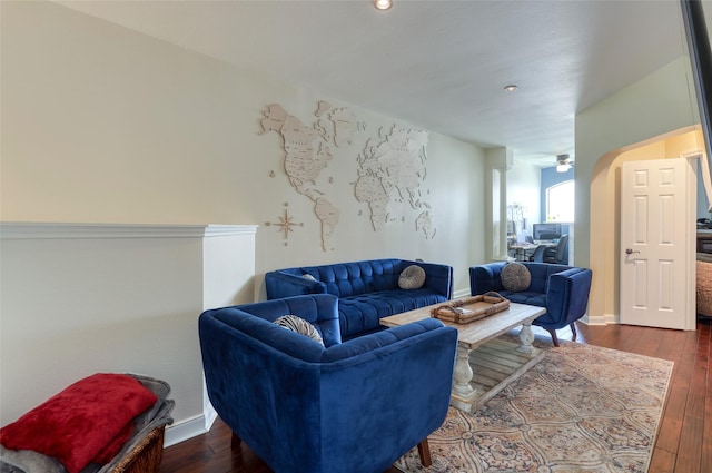 living room featuring arched walkways, ceiling fan, dark wood-type flooring, and baseboards