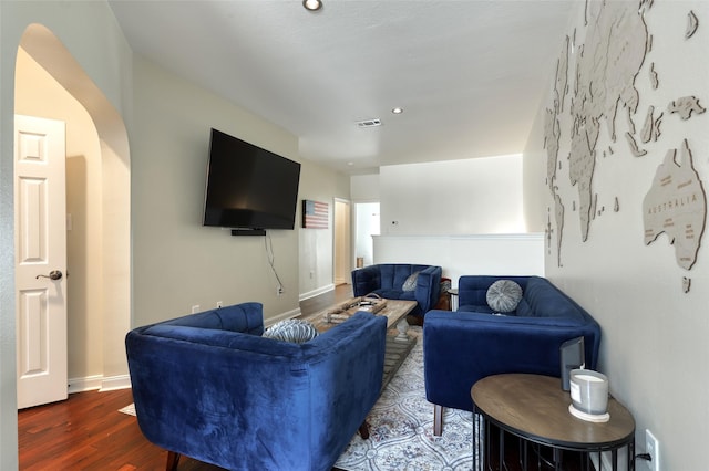 living room featuring arched walkways, wood finished floors, visible vents, and baseboards