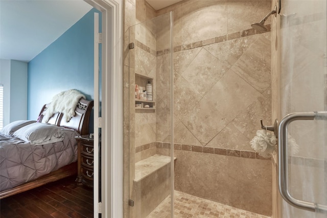 bathroom featuring connected bathroom, a shower stall, and wood finished floors