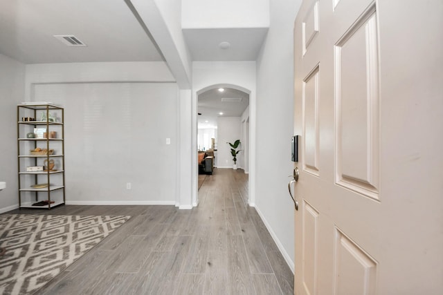 interior space with baseboards, visible vents, arched walkways, and wood finished floors