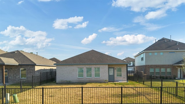 rear view of house featuring brick siding, a yard, and a fenced backyard