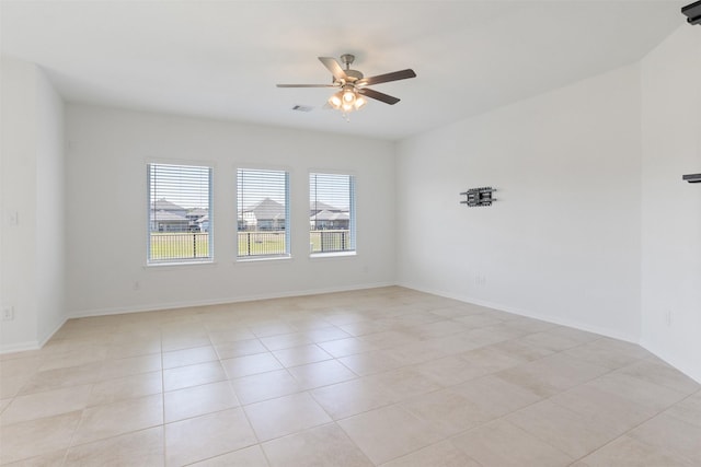 empty room featuring baseboards, light tile patterned floors, visible vents, and a ceiling fan