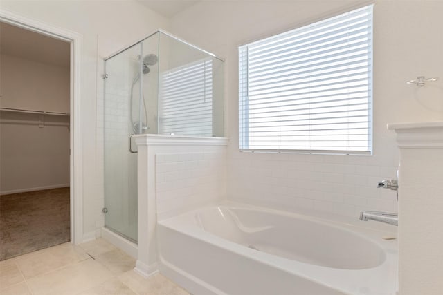 full bathroom featuring a garden tub, tile patterned flooring, a walk in closet, and a shower stall