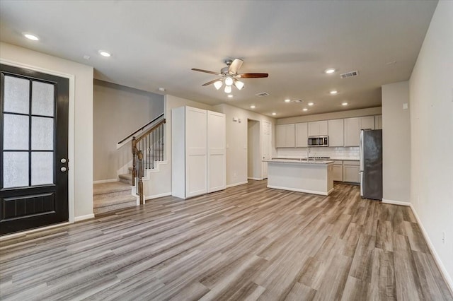 kitchen featuring light wood finished floors, visible vents, baseboards, appliances with stainless steel finishes, and open floor plan