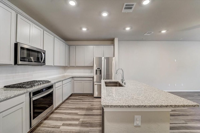 kitchen with a sink, a kitchen island with sink, stainless steel appliances, visible vents, and recessed lighting