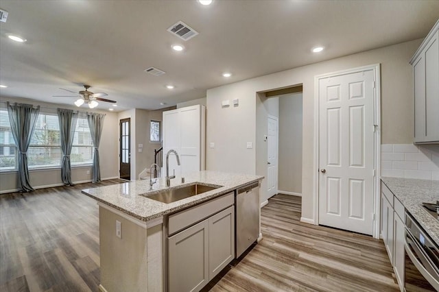 kitchen featuring visible vents, a ceiling fan, a sink, light wood-style floors, and appliances with stainless steel finishes