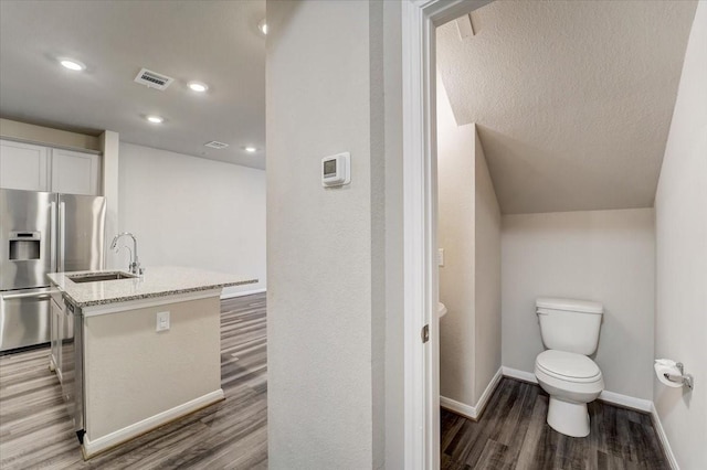 bathroom with wood finished floors, vanity, baseboards, toilet, and visible vents