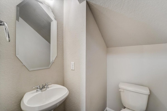 bathroom with lofted ceiling, a sink, and toilet