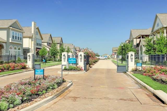 view of street featuring a gate, a residential view, and curbs
